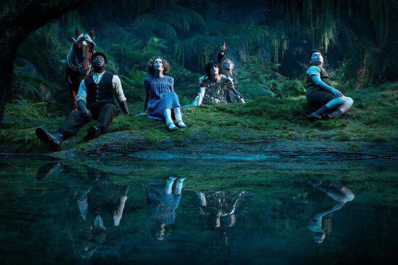The travelers and a cab horse beside a forest pool in a first-look still from Narnia: The Magician’s Nephew